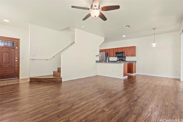 unfurnished living room featuring dark wood-type flooring and ceiling fan