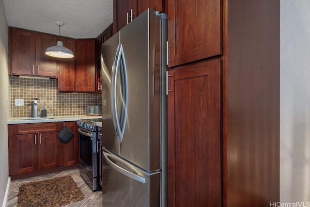 kitchen featuring sink, decorative light fixtures, a textured ceiling, stainless steel appliances, and decorative backsplash