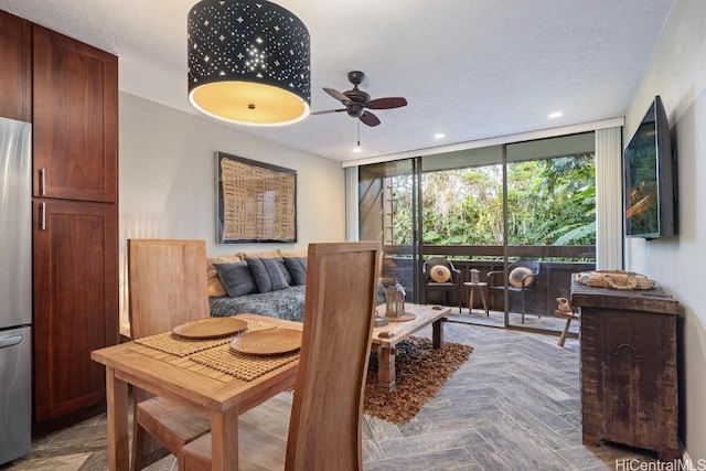 dining area featuring ceiling fan, parquet flooring, a textured ceiling, and a wall of windows