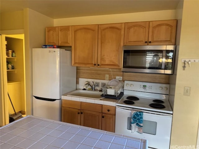 kitchen featuring sink, white appliances, tile counters, and decorative backsplash