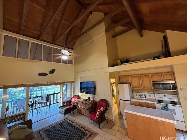 kitchen with sink, white appliances, ceiling fan, tile counters, and beamed ceiling