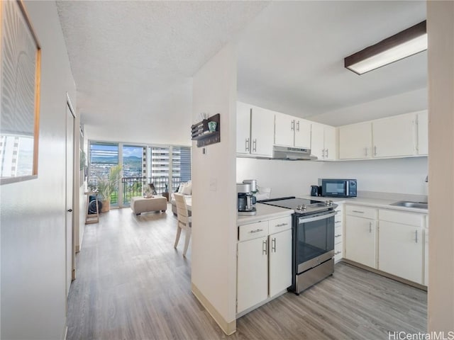 kitchen with white cabinetry, floor to ceiling windows, light wood-type flooring, and stainless steel range with electric stovetop