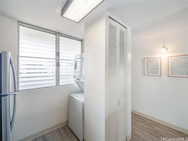 washroom with stacked washer / drying machine, hardwood / wood-style floors, and a textured ceiling