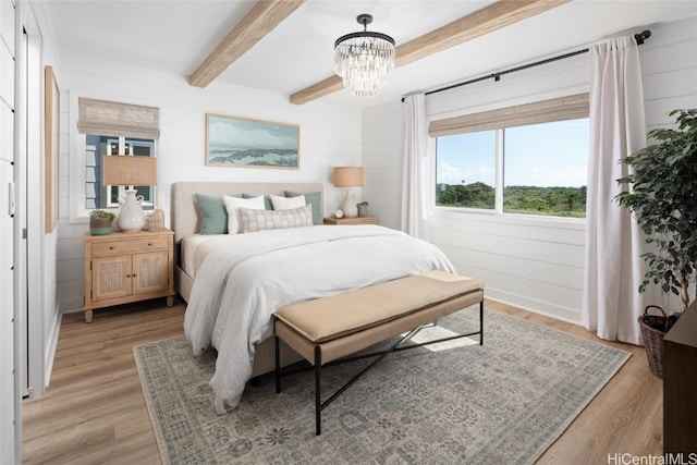 bedroom with beamed ceiling, light hardwood / wood-style floors, and a chandelier