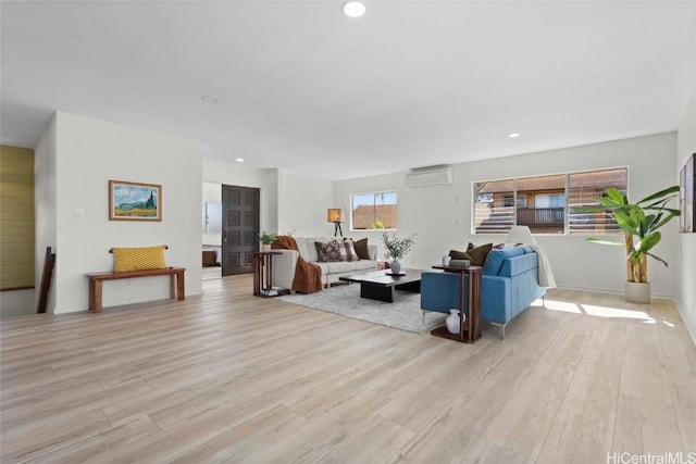 living room with a wall mounted AC and light hardwood / wood-style flooring