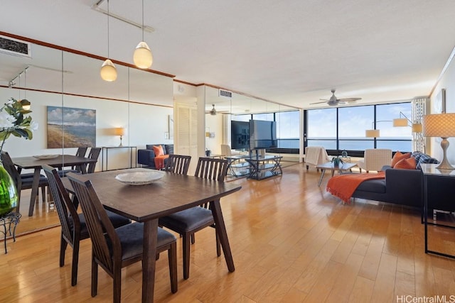 dining space with visible vents, a wall of windows, light wood-style floors, and ceiling fan