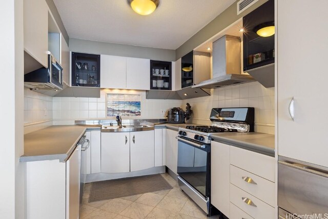 kitchen featuring extractor fan, tasteful backsplash, sink, white cabinets, and stainless steel gas range oven