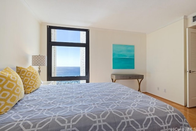 bedroom with a water view, ornamental molding, and hardwood / wood-style floors