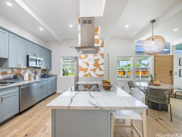 kitchen featuring decorative light fixtures, appliances with stainless steel finishes, a kitchen island, beamed ceiling, and island exhaust hood