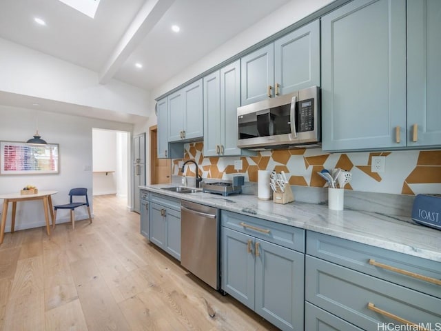 kitchen with appliances with stainless steel finishes, tasteful backsplash, sink, light hardwood / wood-style floors, and beam ceiling