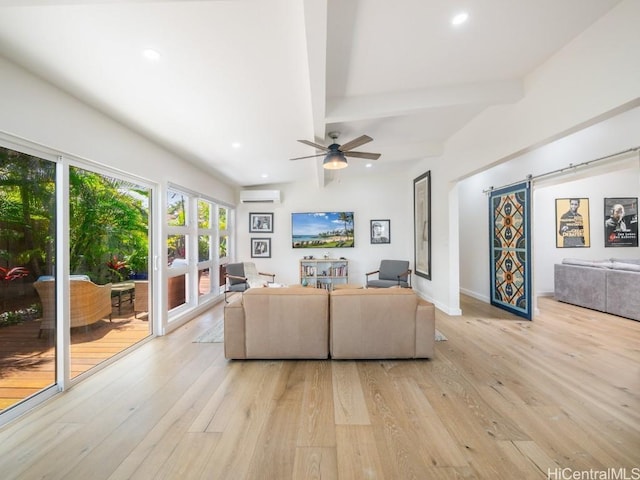 living room featuring beam ceiling, a barn door, a wall mounted AC, and light wood-type flooring