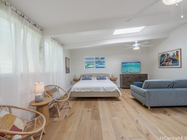 bedroom featuring lofted ceiling with skylight, light hardwood / wood-style floors, and ceiling fan