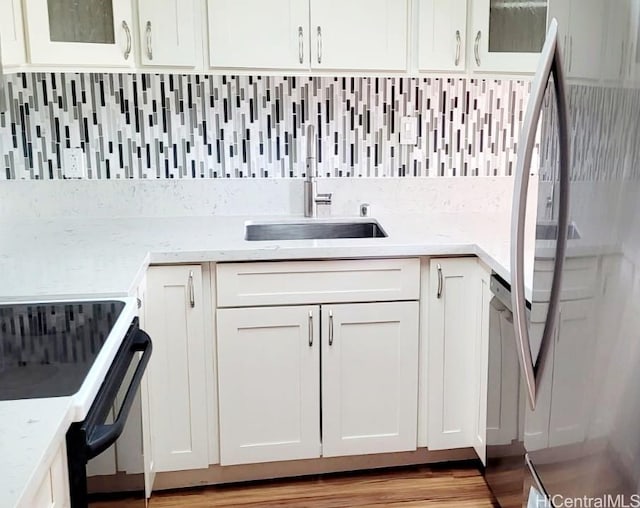 kitchen with tasteful backsplash, black / electric stove, stainless steel fridge, and sink