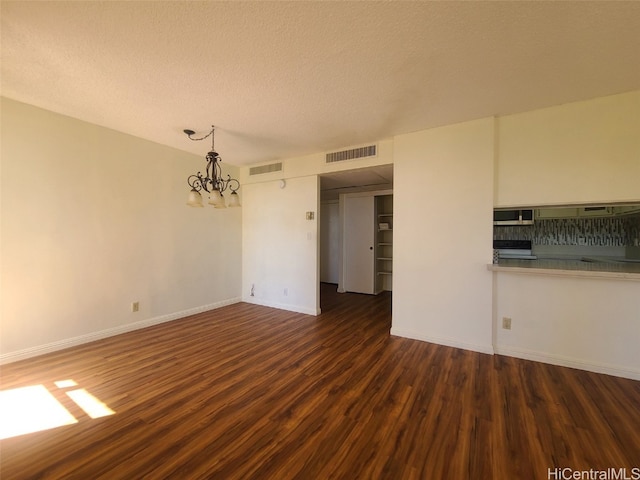 interior space with visible vents, a textured ceiling, wood finished floors, and a chandelier