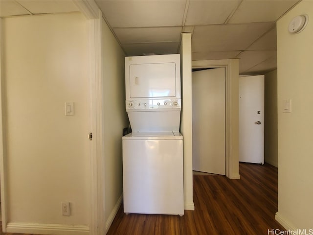 laundry room with dark wood-type flooring, stacked washer / dryer, baseboards, and laundry area