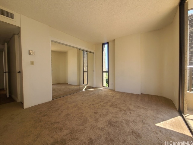 spare room featuring visible vents, a textured ceiling, and carpet floors