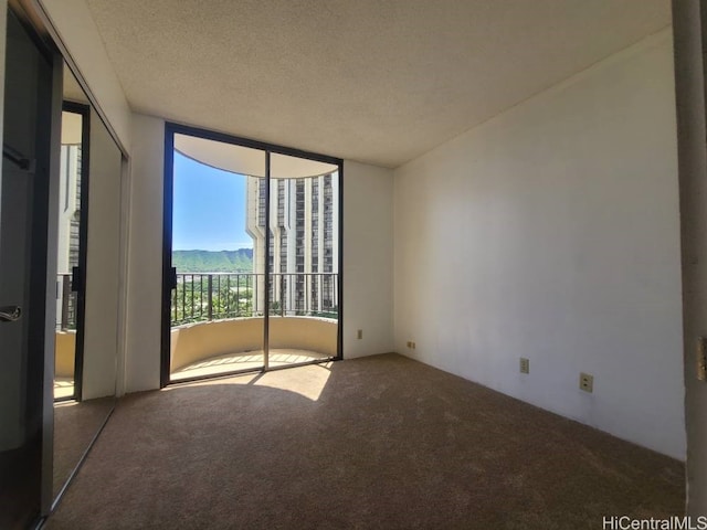 unfurnished bedroom featuring expansive windows, carpet, access to exterior, and a textured ceiling