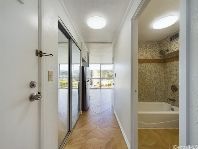 bathroom featuring tiled shower / bath, tile patterned floors, ornamental molding, and a textured ceiling