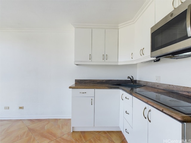 kitchen featuring light tile patterned floors, crown molding, sink, black electric stovetop, and white cabinets