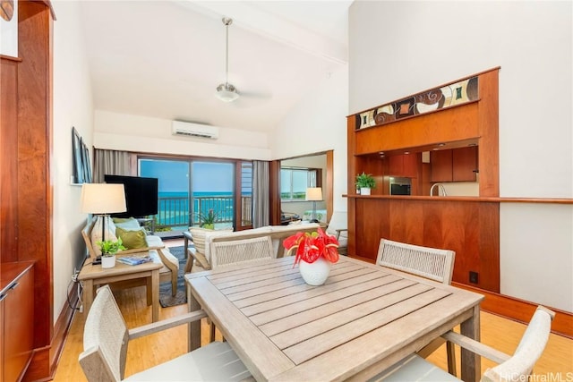 dining area with an AC wall unit, lofted ceiling, light hardwood / wood-style flooring, breakfast area, and ceiling fan