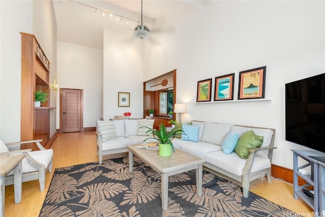 living room with light hardwood / wood-style floors, track lighting, and a high ceiling