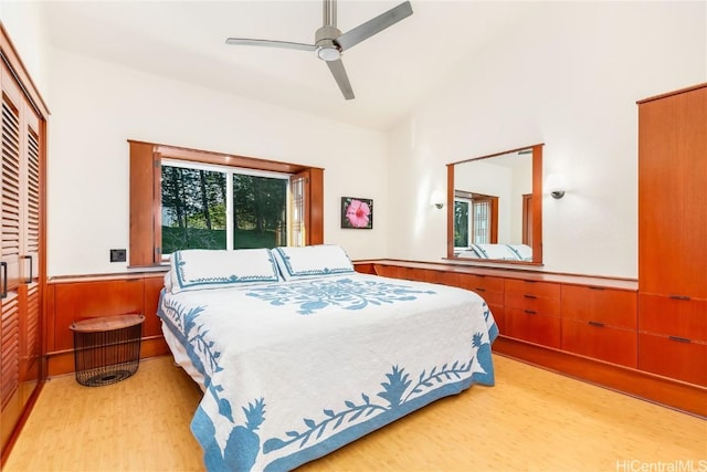 bedroom with light hardwood / wood-style flooring, ceiling fan, vaulted ceiling, and wooden walls