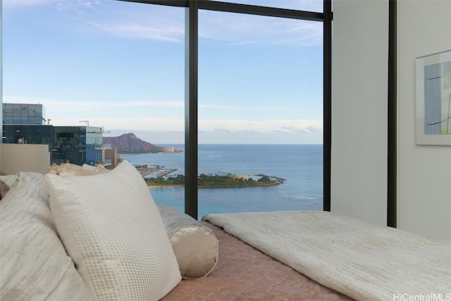 bedroom with multiple windows, a water view, and a wall of windows