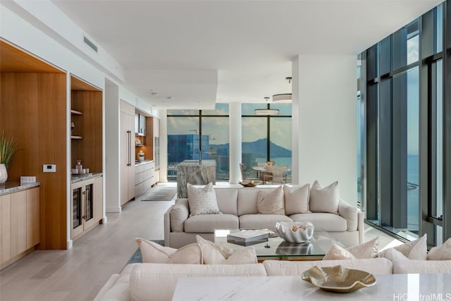 living room featuring a mountain view, sink, a wall of windows, and light hardwood / wood-style floors