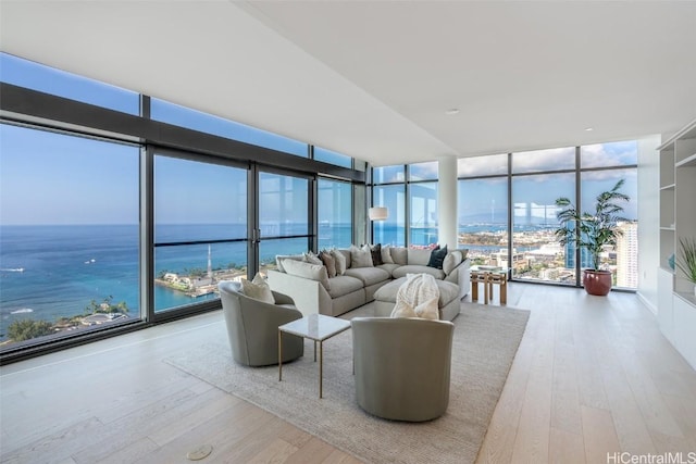 living room featuring a water view, a wall of windows, and light hardwood / wood-style flooring