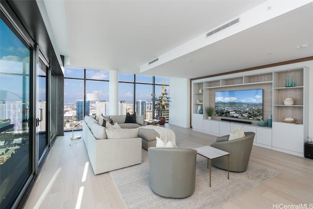 living room featuring built in features, floor to ceiling windows, and light hardwood / wood-style flooring