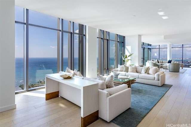 living room featuring light wood-type flooring, floor to ceiling windows, and a water view