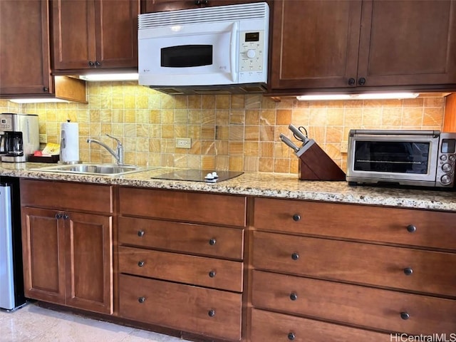 kitchen featuring tasteful backsplash, black electric cooktop, sink, and light stone counters