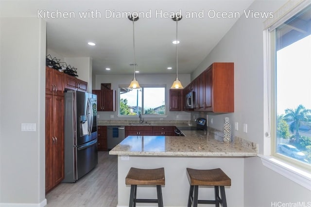 kitchen with sink, stainless steel appliances, a kitchen breakfast bar, decorative light fixtures, and kitchen peninsula