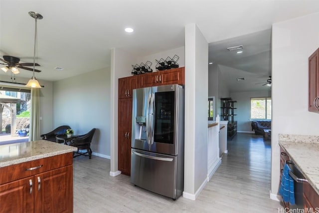 kitchen with ceiling fan, stainless steel refrigerator with ice dispenser, light stone counters, light hardwood / wood-style floors, and decorative light fixtures