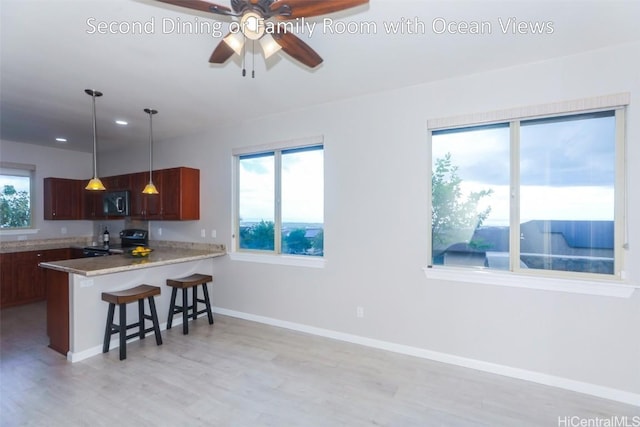 kitchen featuring pendant lighting, black range with electric cooktop, plenty of natural light, and kitchen peninsula