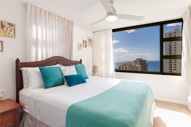 bedroom with a water view, ceiling fan, carpet flooring, and a wall of windows