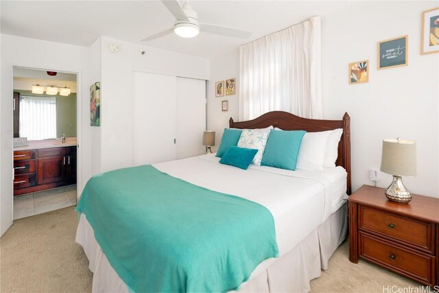 carpeted bedroom featuring ceiling fan, ensuite bathroom, and a closet