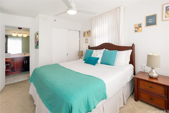 bedroom with ceiling fan, light colored carpet, connected bathroom, and a closet