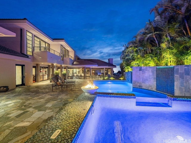 pool at dusk with a patio and an outdoor fire pit