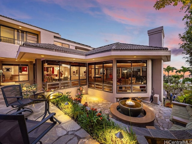 back house at dusk featuring a fire pit and a patio area