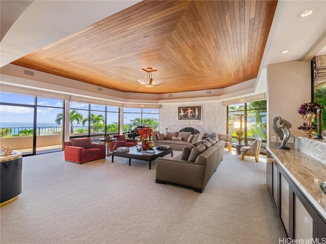 living room featuring a water view, a tray ceiling, a wealth of natural light, and wooden ceiling