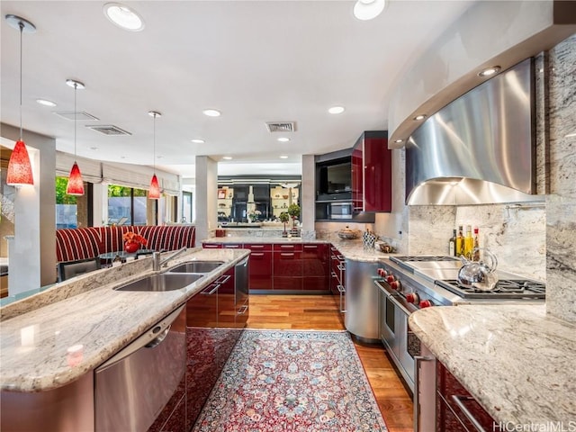 kitchen with a spacious island, sink, appliances with stainless steel finishes, pendant lighting, and light stone countertops