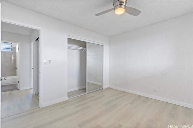 unfurnished bedroom featuring light hardwood / wood-style flooring, a textured ceiling, ceiling fan, and a closet