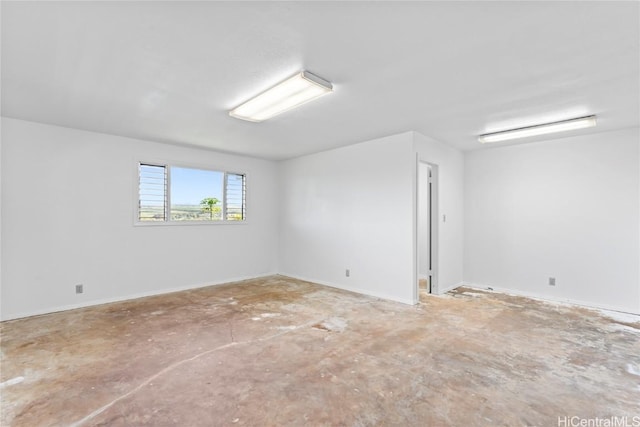 empty room with unfinished concrete floors and baseboards