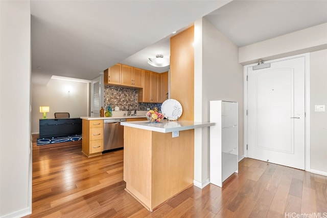 kitchen with a breakfast bar, kitchen peninsula, dishwasher, light hardwood / wood-style floors, and decorative backsplash