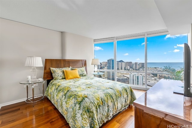 bedroom featuring a wall of windows, hardwood / wood-style floors, and multiple windows