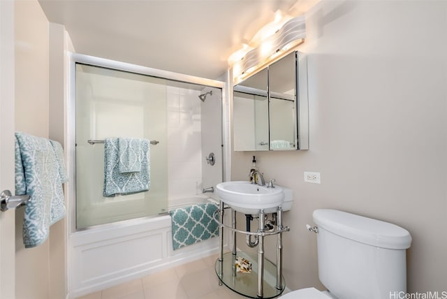 bathroom with tile patterned flooring, shower / bath combination with glass door, and toilet