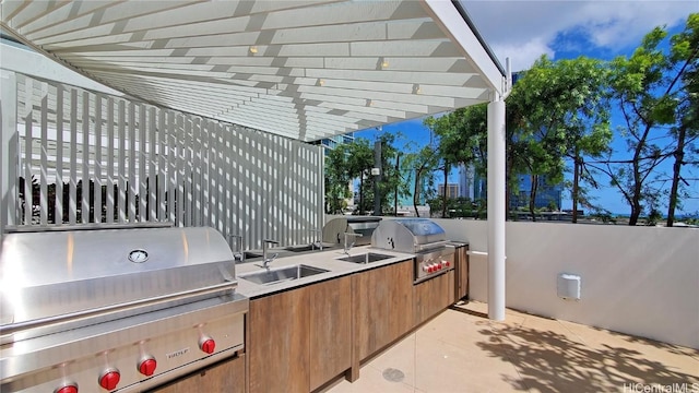 view of patio / terrace featuring area for grilling, sink, a pergola, and exterior kitchen