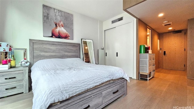 bedroom with light hardwood / wood-style floors and a closet