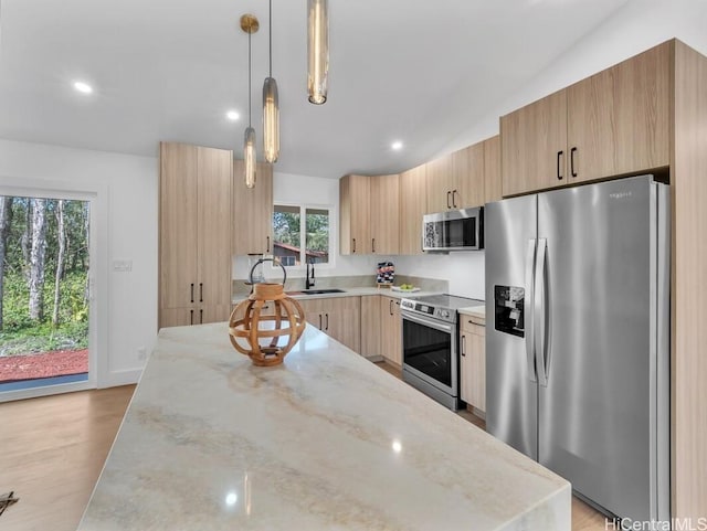 kitchen with light stone counters, pendant lighting, stainless steel appliances, and light brown cabinets